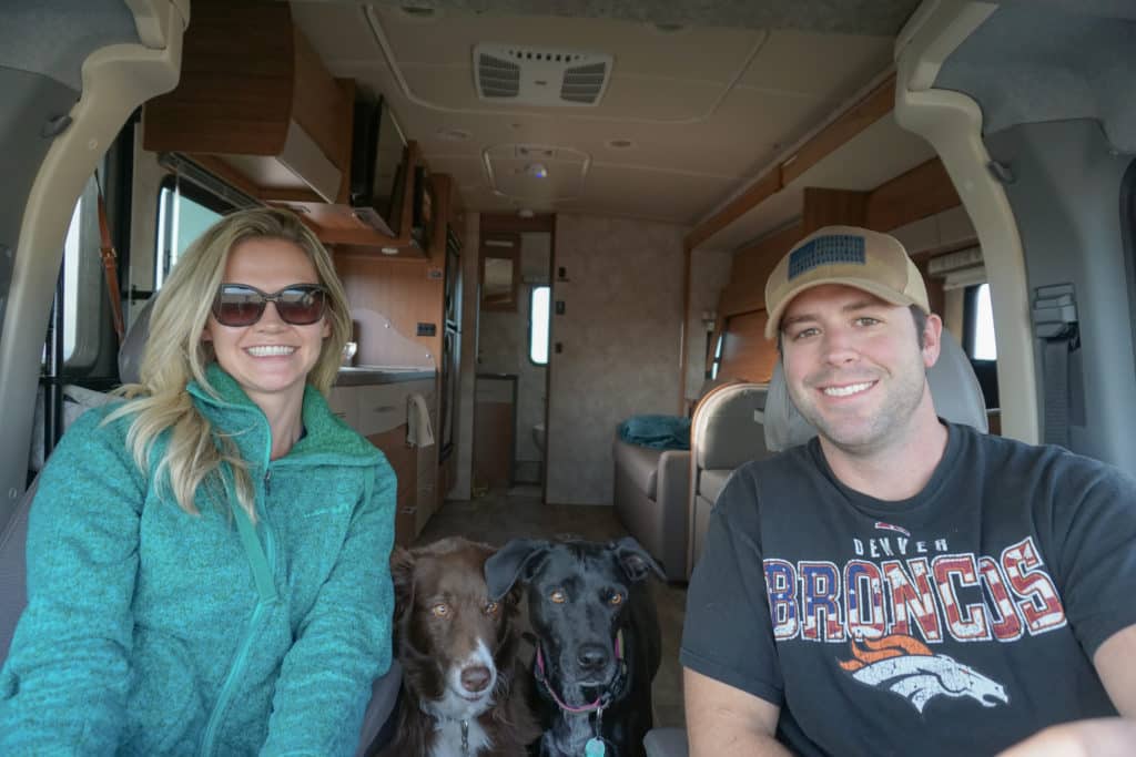 Young couple driving a motorhome with 2 dogs between them