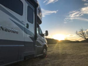 RV motorhome in open space with sun setting