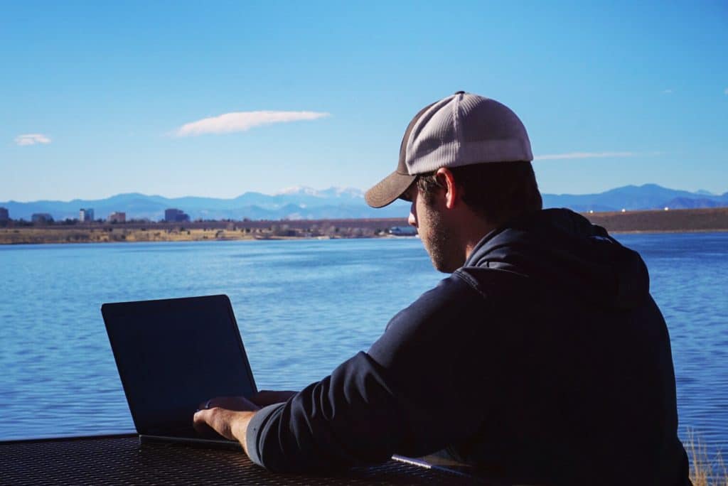 Man working on laptop by a lake