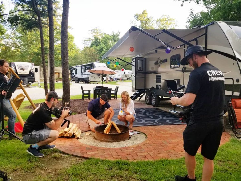video crew filming a couple camping by an RV
