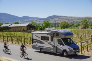 Couple riding bikes next to motohome parked at a vineyard using Harvest Hosts membership