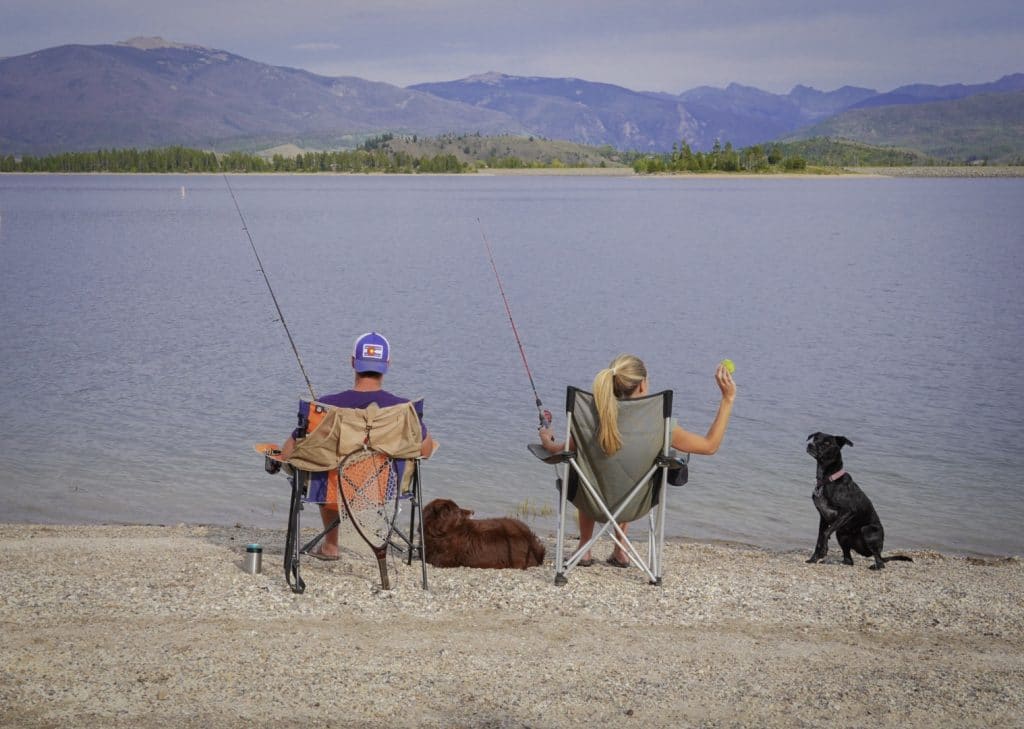 couple and two dogs sitting on shore Fishing at Grand Lake, Colorado