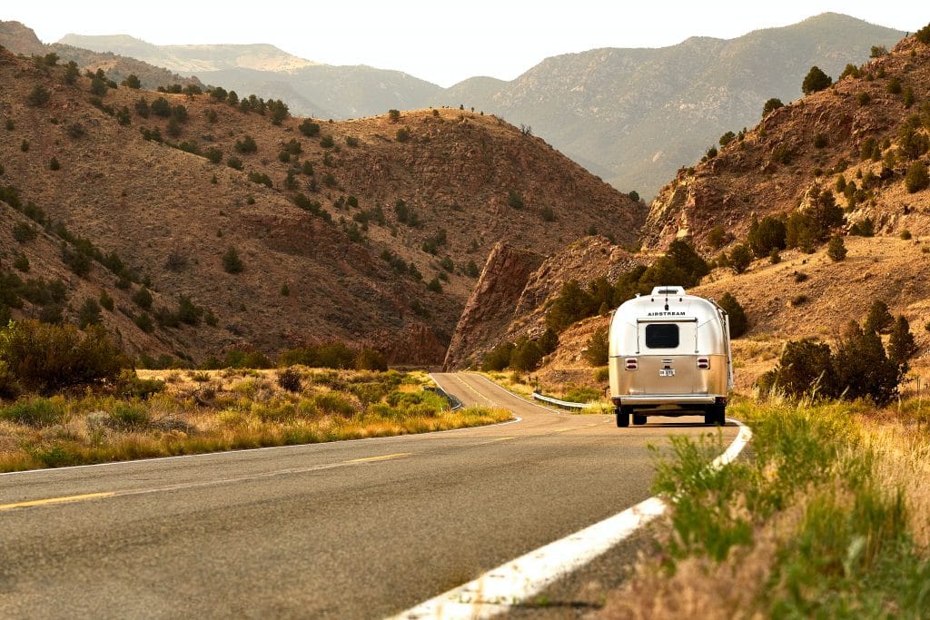 Airstream camper being towed on a scenic mountain road