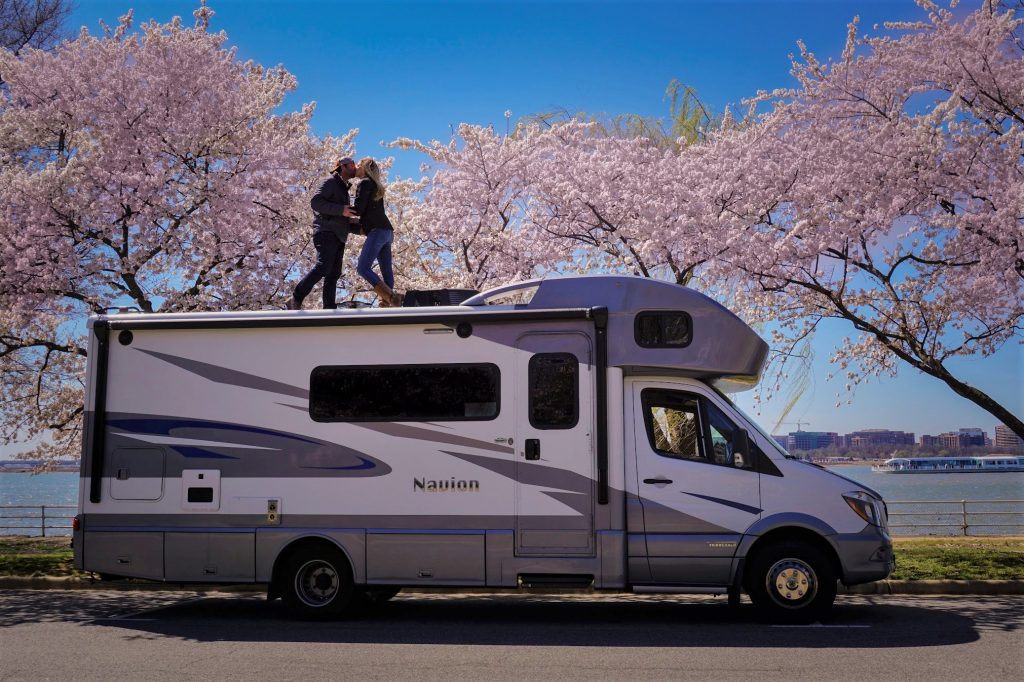 Couple kissing on the roof of an RV under cherry blossom trees